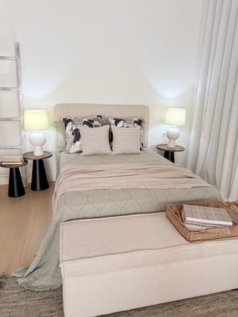 Dormitorio con ropa de cama beige y lámpara
